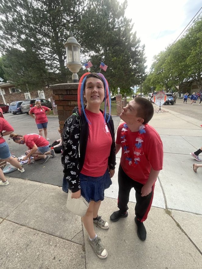 Client and staff member participating in a 4th of July parade, exemplifying community engagement and social participation in festivities.