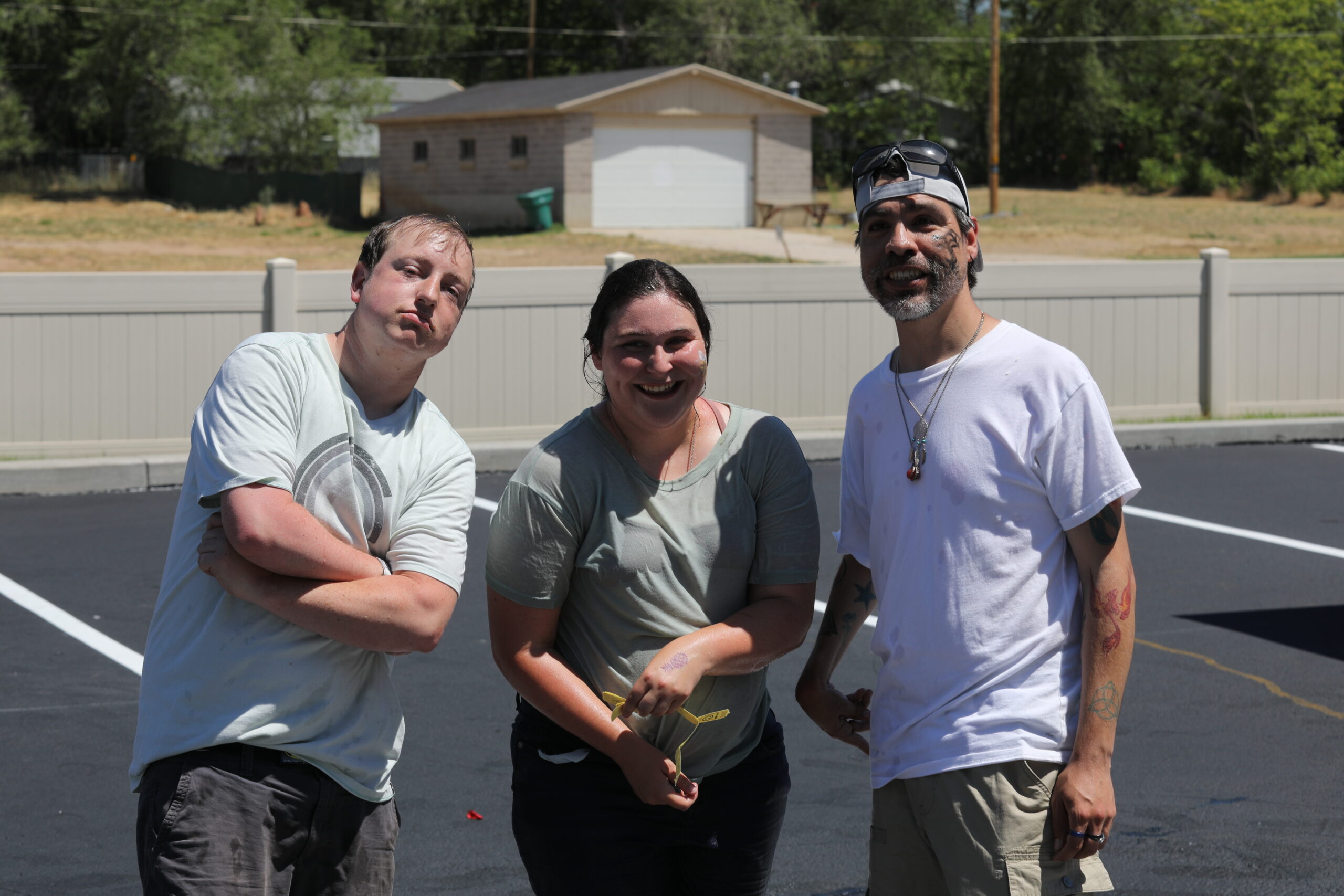 A group of three individuals smiling and posing during a car wash event.